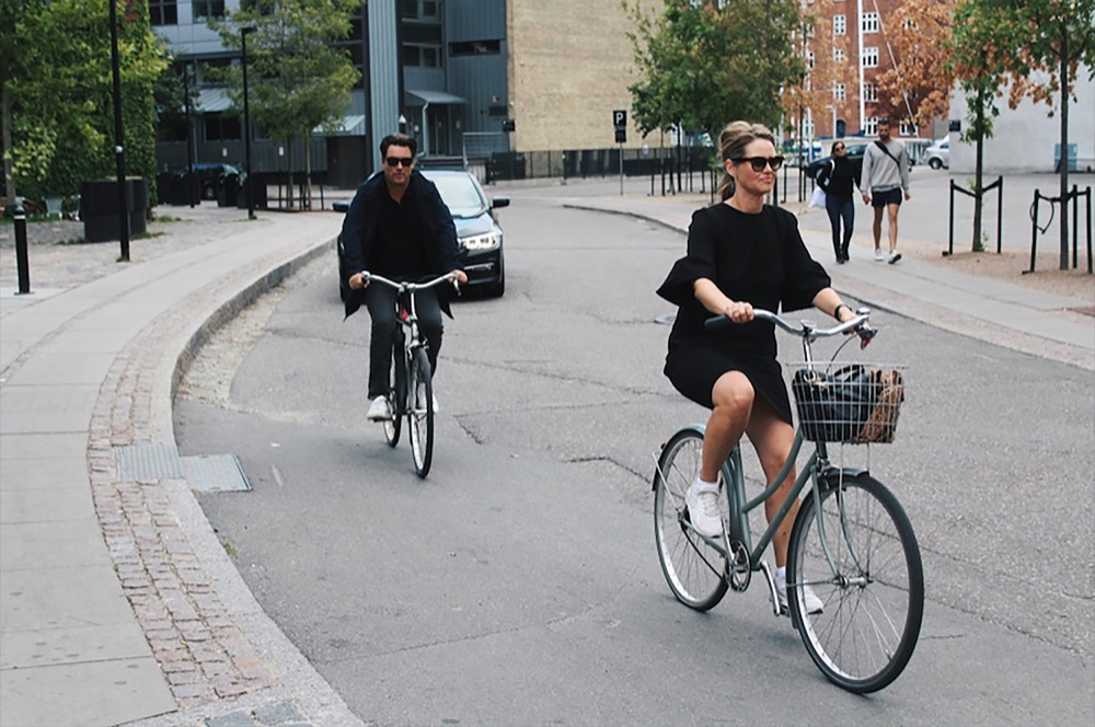 Two cyclists riding a curving Copenhagen street