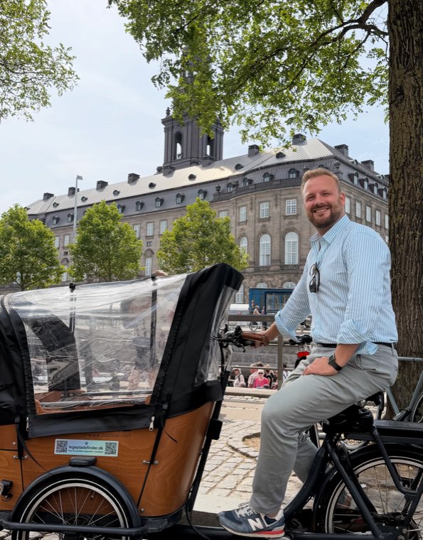 Oliver Wang Hansen seated on his cargo bike, looking over his shoulder towards the camera