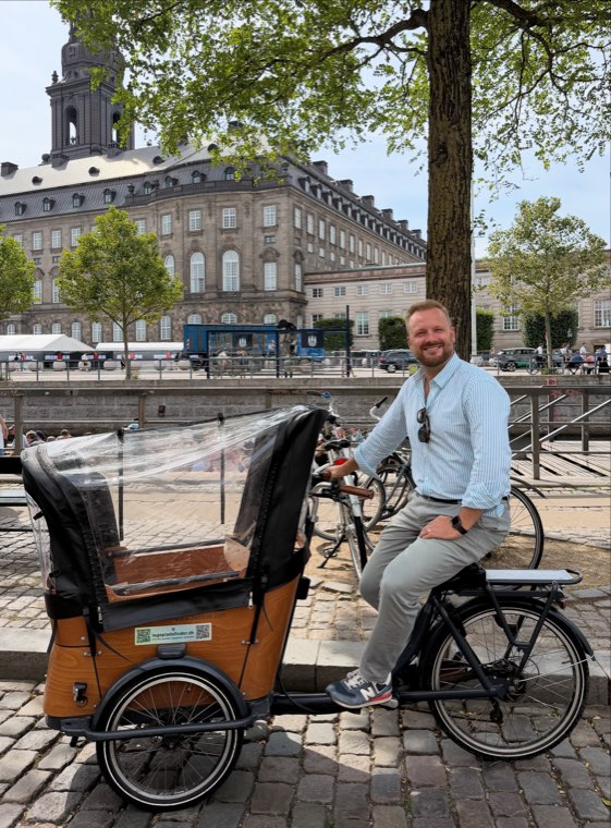 Oliver Wang Hansen on his cargo bike with the canal and a palace facade in the background