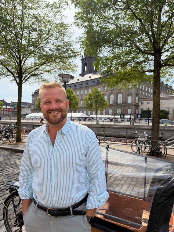 Close portrait of Oliver Wang Hansen standing next to his cargo bike in Copenhagen